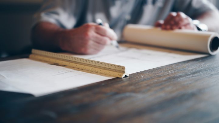 Mann arbeitet an Architekturplänen mit Lineal