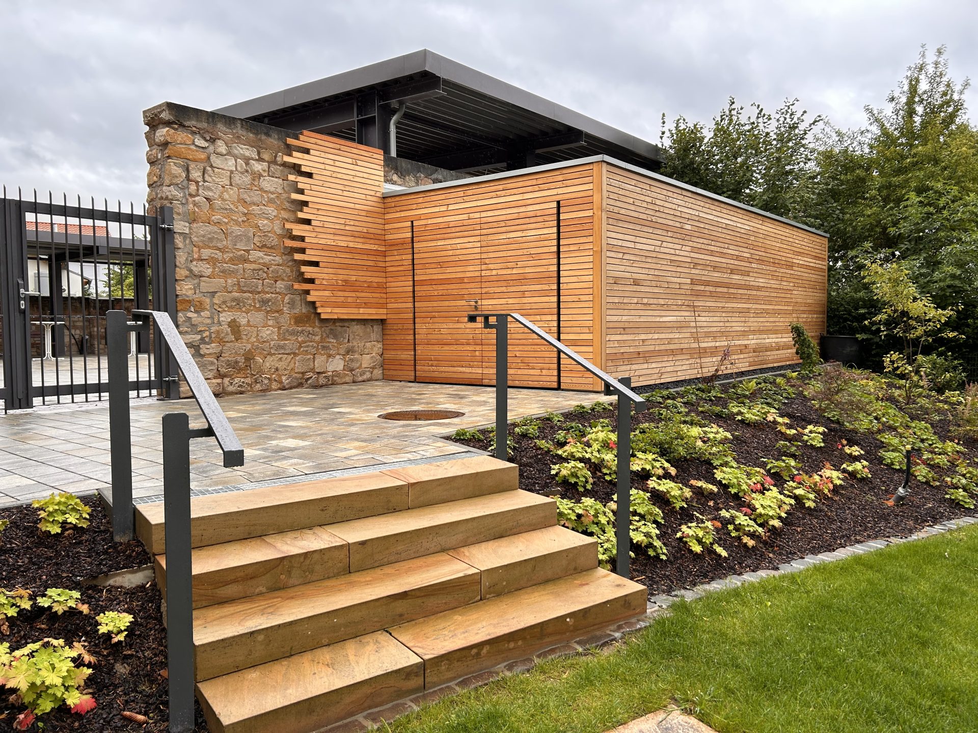 Moderne Holzarchitektur mit Steintor und Garten