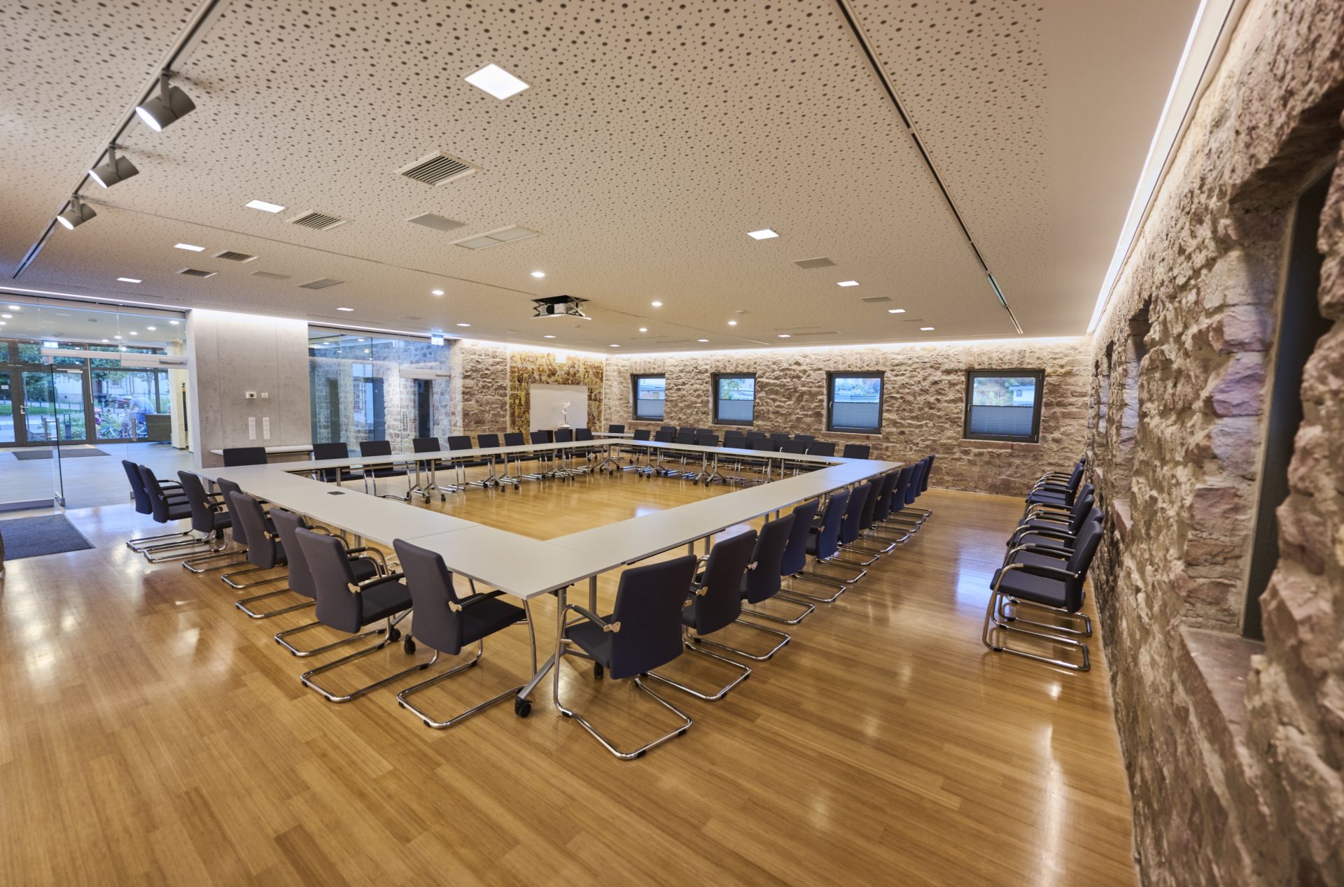Moderner Konferenzraum mit Steinwand und Holzboden