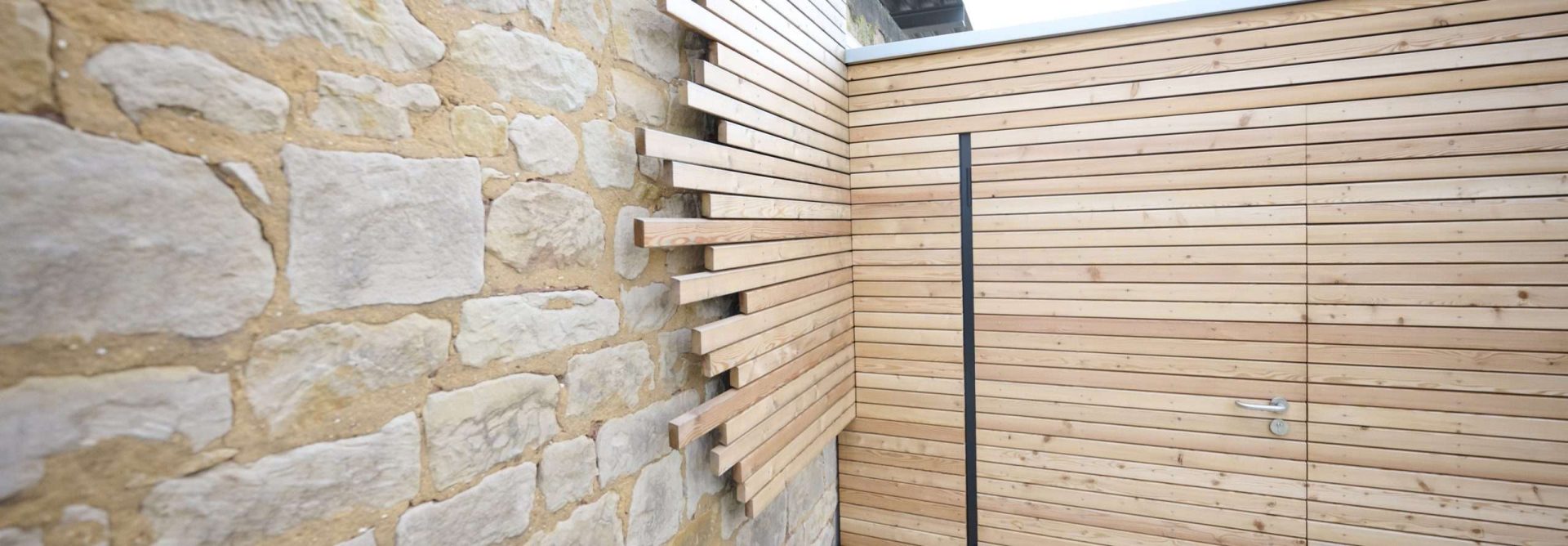 Steinmauer neben moderner Holzwand